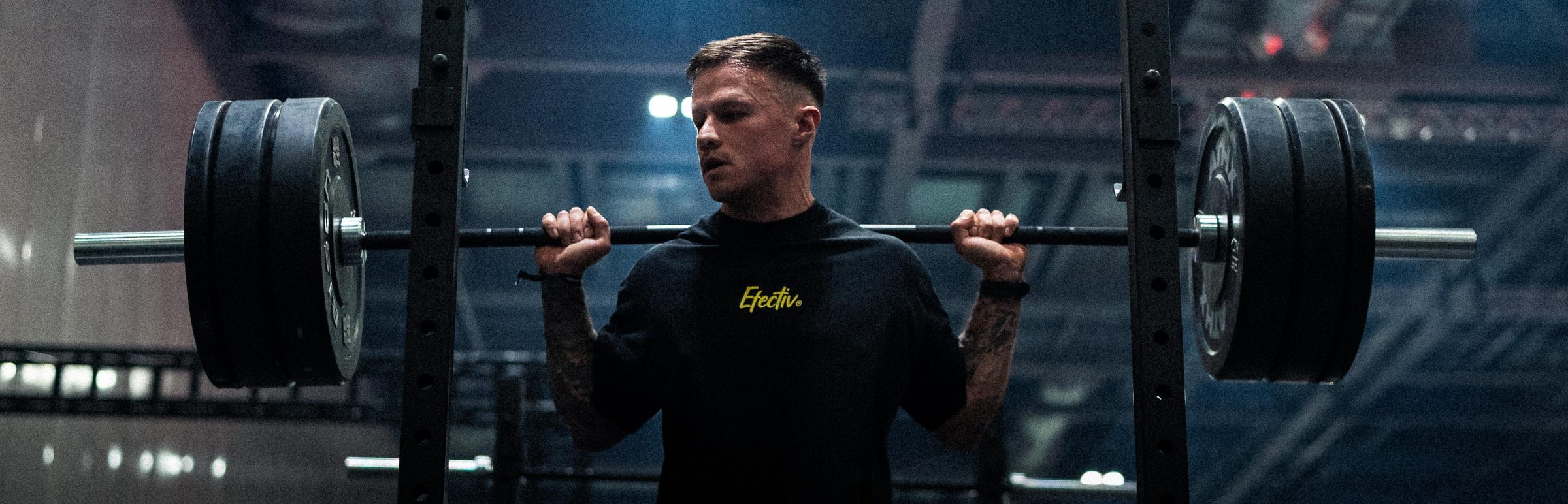 Athlete with a loaded barbell across his shoulders at ATHX