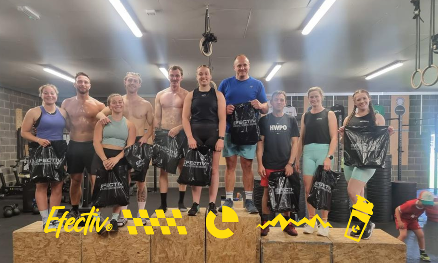 Group of people on wooden boxes holding black Efectiv bags in a gym