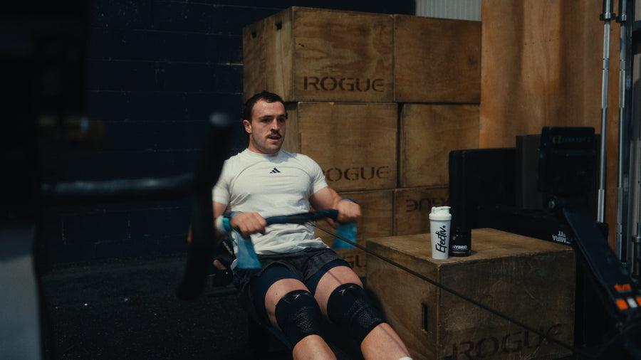Man using a rowing machine in a gym, with an Efectiv shaker on a box