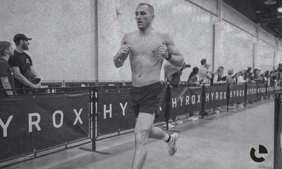 Man running past HYROX branded barriers at a race, in black and white